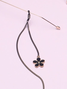 Détail de la chaîne de lunettes dorée avec fleurs en émail noir et boucles en caoutchouc