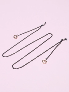 Détail d'une chaîne à lunettes noire avec deux pendentifs cœurs évidés en or rose