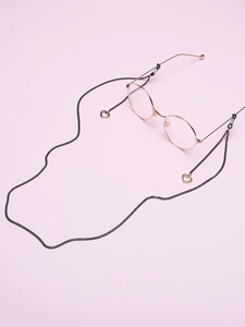 Détail d'une chaîne de lunettes noire avec pendentifs cœur en or rose et lunettes rondes