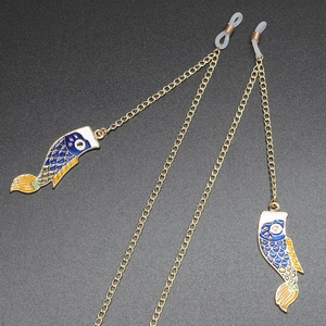 Golden metal glasses chain with blue enamel koi carp pendant on textured dark background