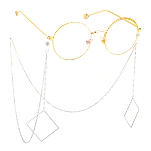 Golden round glasses with silver metal chains and geometric diamond pendants on white background