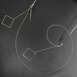 Detail of gold metal glasses chain featuring geometric square pendants and silicone loops