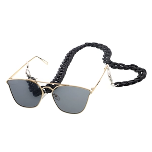 Detail of pilot sunglasses with a thick black acrylic decorative chain strap and gold metal frame