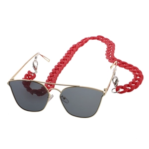 Detail of red acrylic chain links attached to gold metal sunglasses frame