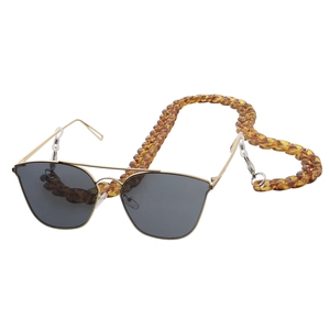 Detail of amber tortoiseshell acrylic eyewear chain on classic gold frame sunglasses