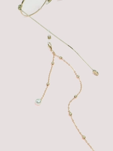 Detail of gold glasses chain featuring small beads, a pearl drop, and silicone loops