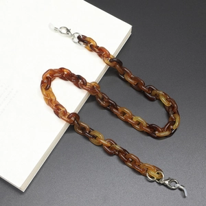 Macro detail of amber acrylic eyewear chain with metal lobster clasps and silicone loops
