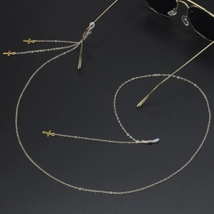 Chaîne de lunettes dorée antidérapante avec pendentifs croix et pompons sur fond noir