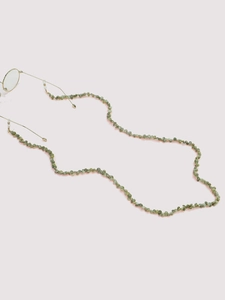 Detail of green stone beads and gold chain on stylish eyewear strap with rubber ends