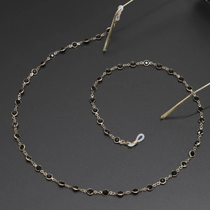 Fashionable golden eyeglass chain with black beads and silicone loops on black background