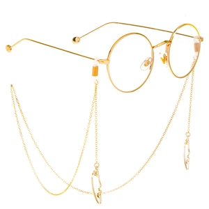 Golden round glasses with delicate beaded chain and hollow metal pendant on white background