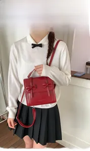 Detalle del bolso bandolera de PU rojo con lazos elegantes y logo de AXIX & HAOS grabado