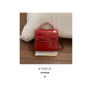 Detalle de una elegante mochila de cuero rojo con lazos decorativos y textura brillante