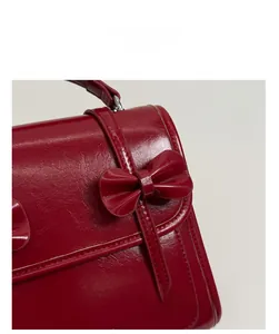 Detalle de bolso en cuero pulido burdeos con lazo 3D y costuras finas