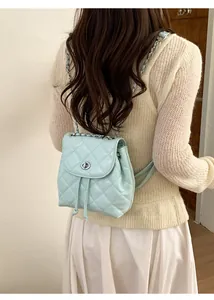 Detail of mint green quilted backpack with chain strap on model's back
