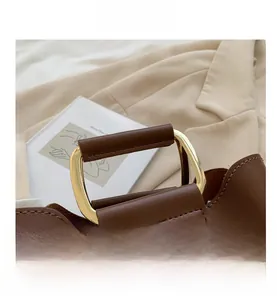 Detail of a brown lychee-grain leather handbag with a gold-tone metal and leather handle