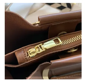 Detailed close-up of smooth gold metal zipper and premium leather texture on bucket bag