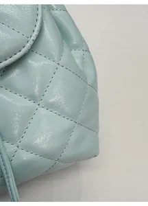 Detailed macro view of light blue quilted leather texture and fine stitching on the bag