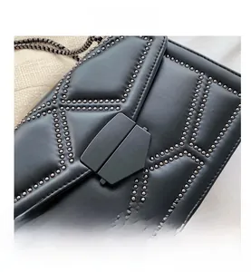 Detailed close-up of a black leather crossbody bag with punk style metal rivet patterns