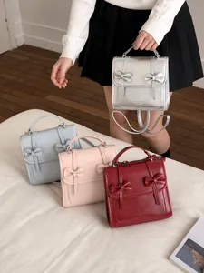 Dettaglio di quattro borse a patta in pelle PU colorate con fiocchi decorativi