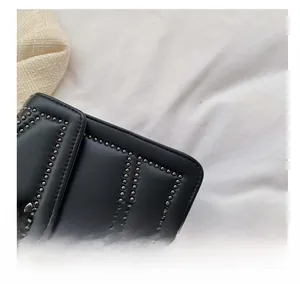 Detail of black leather square bag showing silver stud accents and neat stitching