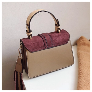 Detail view of contrast color handbag with suede flap and striped fabric shoulder strap