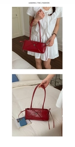 Detail view of a red sleek faux leather shoulder bag with bow knot and heart charm