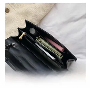 Detail view of black square bag interior with compartments holding phone and cosmetics