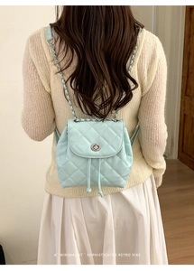 Rear view of light blue quilted leather backpack with silver chain straps and turn-lock