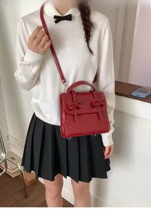 Bolso bandolera rojo oscuro con lazo en cuero charol brillante y conjunto blanco