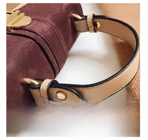 Detailed close-up of dark red suede handbag with golden buckle and leather handle