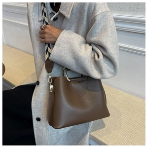 Brown leather bucket bag detail with gold metal handle and chevron pattern wide strap