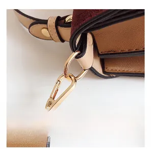 Detail of detachable shoulder strap with golden lobster clasp and leather textures