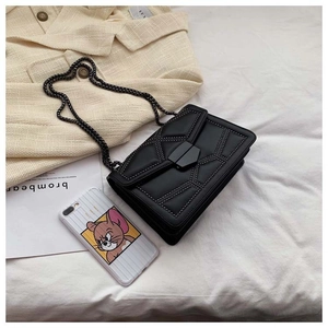 Close-up of black crossbody bag with metallic chain and studded geometric pattern