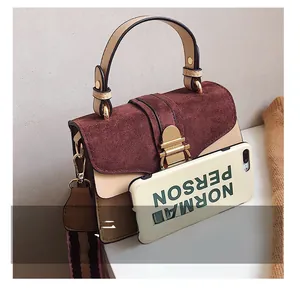 Detail showing the retro color-block handbag with wide striped shoulder strap next to a phone