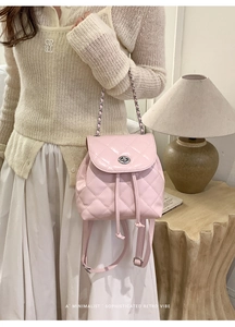 Detail showing high-gloss light pink quilted mini backpack with metal chain and buckle