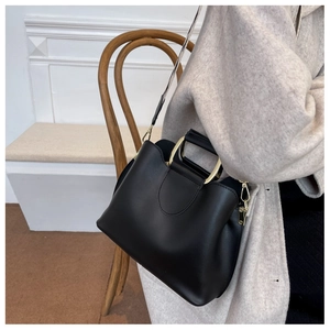 Close-up of black leather bucket bag with gold metal handle and patterned wide strap