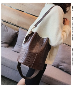 Detail of brown crocodile pattern bucket bag with interchangeable wide fabric strap