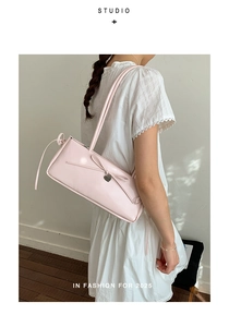 Close-up of pink shoulder bag with bow and heart charm worn over white lace dress