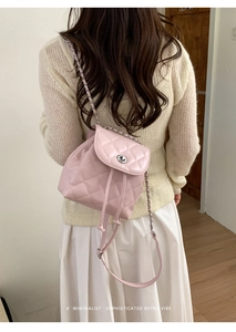 Detailed view of pink quilted mini backpack with metal turn-lock and chain strap on model