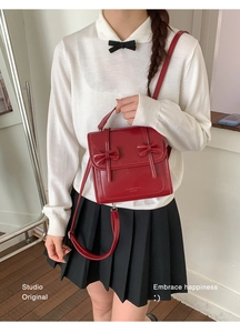 Detalle del bolso rojo de estilo vintage con lazos decorativos y acabado brillante
