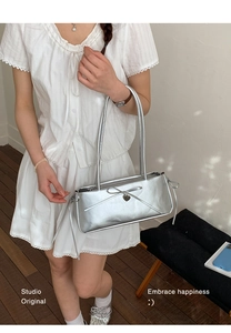 Detail of silver metallic shoulder bag with ribbon bow and heart pendant charm