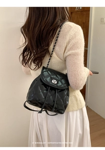 Detail of a black quilted leather backpack with silver turn-lock and chain strap
