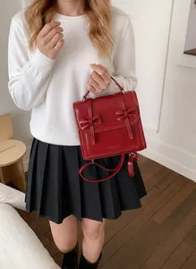 Dettaglio zaino rosso in pelle PU con fiocchi eleganti e manico per il trasporto a mano