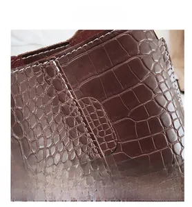 Detailed macro shot of coffee brown crocodile pattern leather with white stitching
