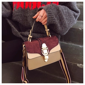 Detail of color-block crossbody bag featuring wine red suede and striped woven shoulder strap