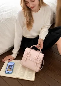 Zaino in pelle opaca rosa con fiocchi decorativi e manico superiore in scena lifestyle
