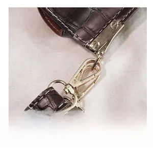 Detail showing polished gold hardware and crocodile embossed leather on shoulder bag