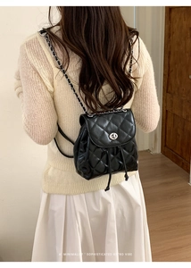 Detail of black quilted leather backpack with metal chain strap and turn-lock closure