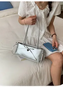 Detailed shot of a silver bow shoulder bag with heart pendant on a white background